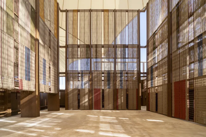 Interior courtyard with woven timber screens filtering daylight onto polished concrete floor and timber columns