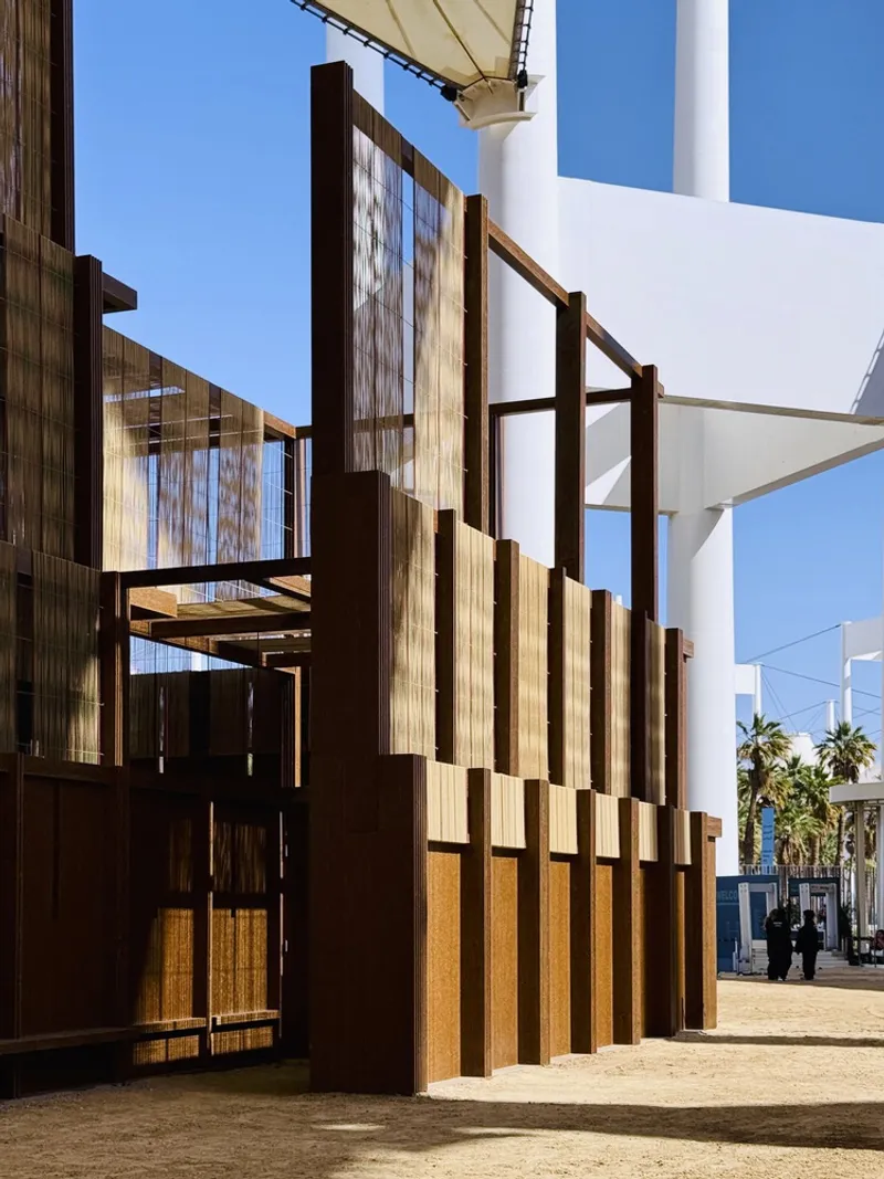 Angled view of timber screen panels with horizontal beams framing openings under a clear sky