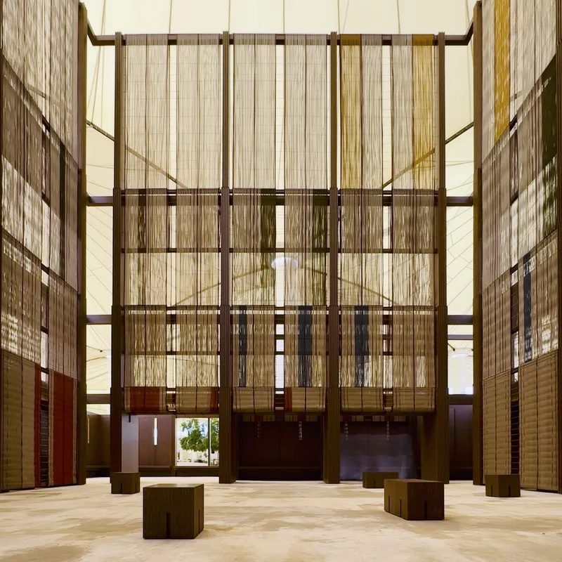 Central atrium space with suspended translucent panels and dark timber benches on polished stone floor