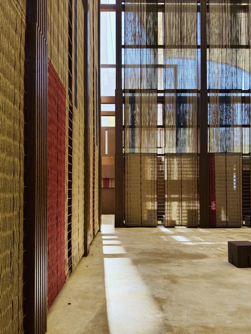 Corner detail showing red louvered wall panel beside woven fiber screens and polished concrete floor