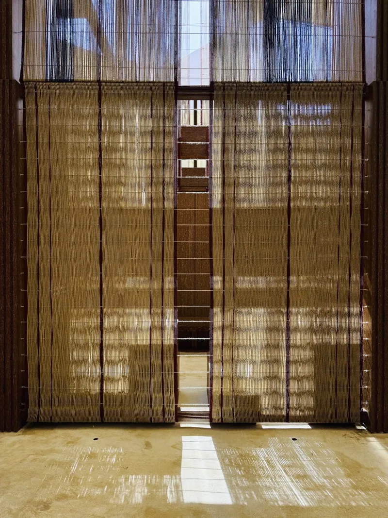 Tall woven fiber doors in timber frame with sunlight streaming through onto the interior floor