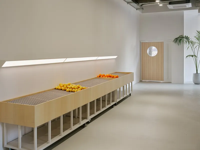 Long timber and mesh display counter with citrus fruit arranged beside a wood-paneled door