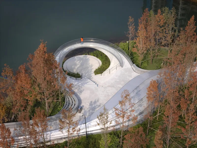 Top-down view of the spiraling white concrete path with circular courtyard and autumn trees
