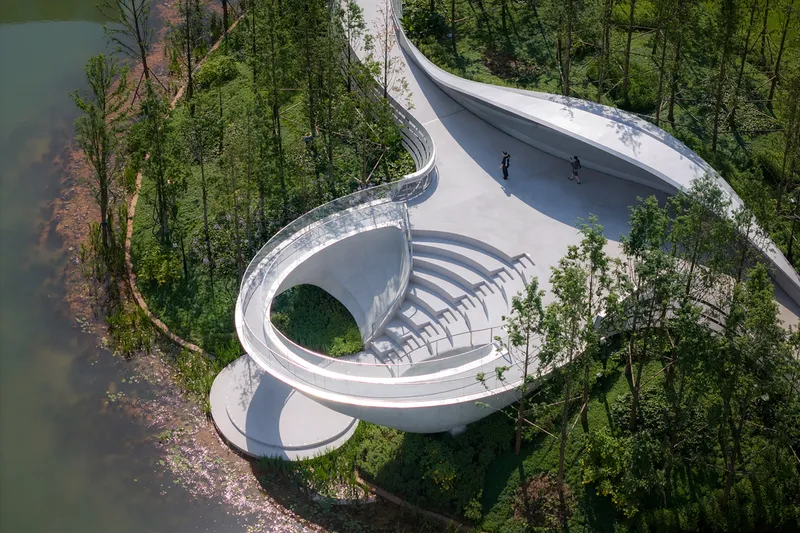 Drone view of spiral amphitheater with concentric seating steps descending around a central planted opening