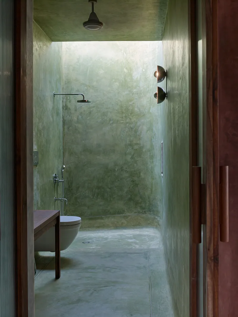 Bathroom with green polished plaster walls and ceiling lit by a skylight