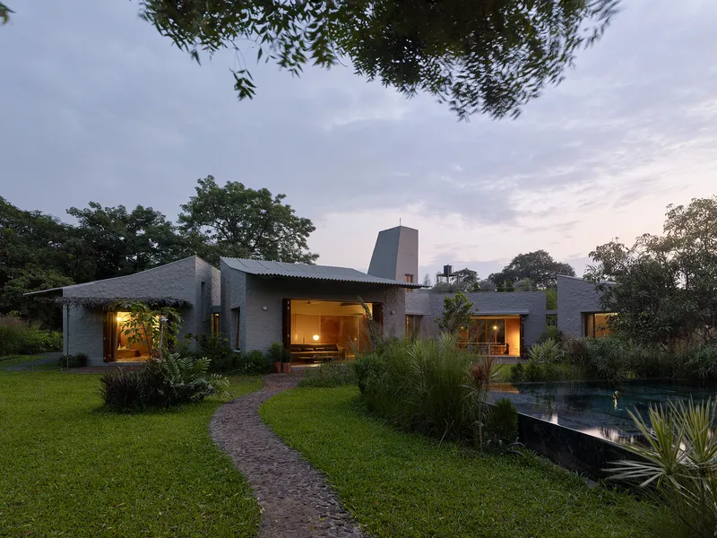 Garden facade with corrugated metal roofs and reflecting pool at dusk