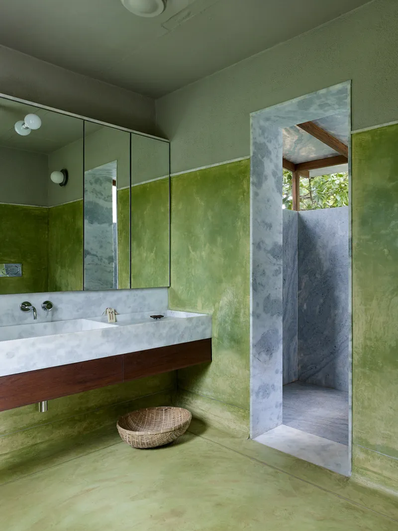 Bathroom with green lime-washed walls, grey concrete portal and floating timber vanity with marble countertop