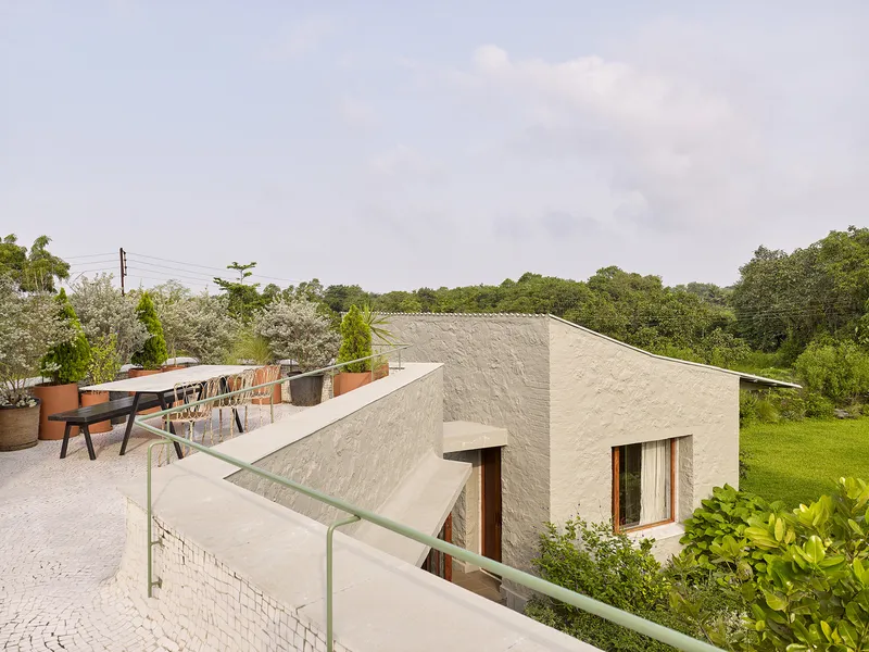 Rooftop terrace with dining furniture and planted pots overlooking tree canopy under overcast skies