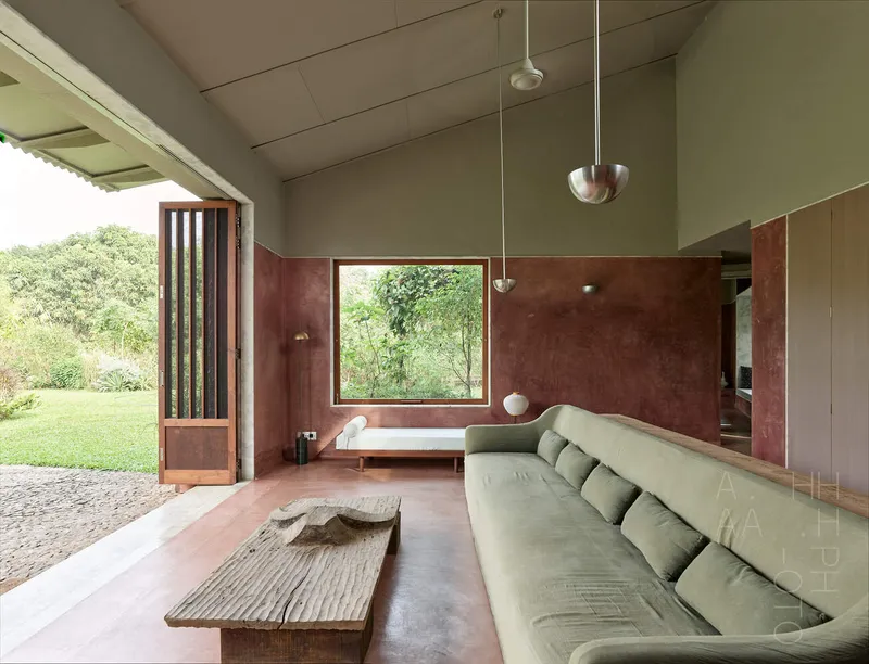 Living room with olive-green walls, maroon plaster dado and pendant lights overlooking lawn through timber doorway