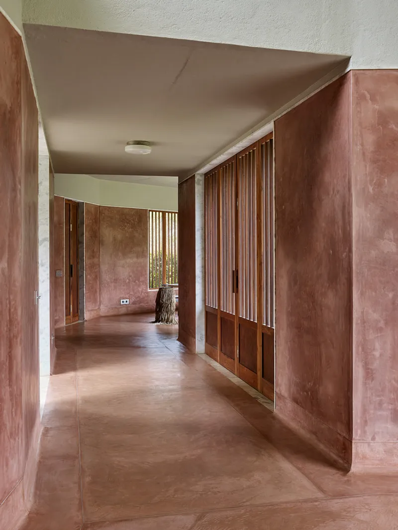 Corridor with vertical timber slat screen and terracotta-finished walls under a clerestory window