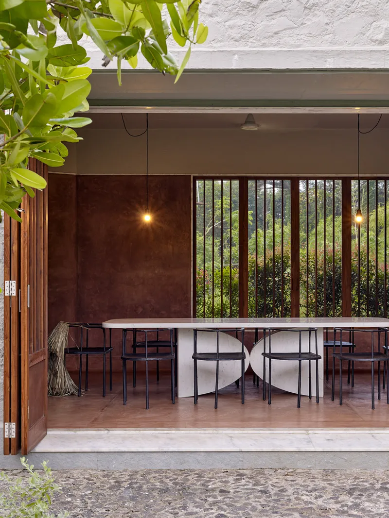 Covered dining terrace with long table and chairs framed by timber screens and pendant lights