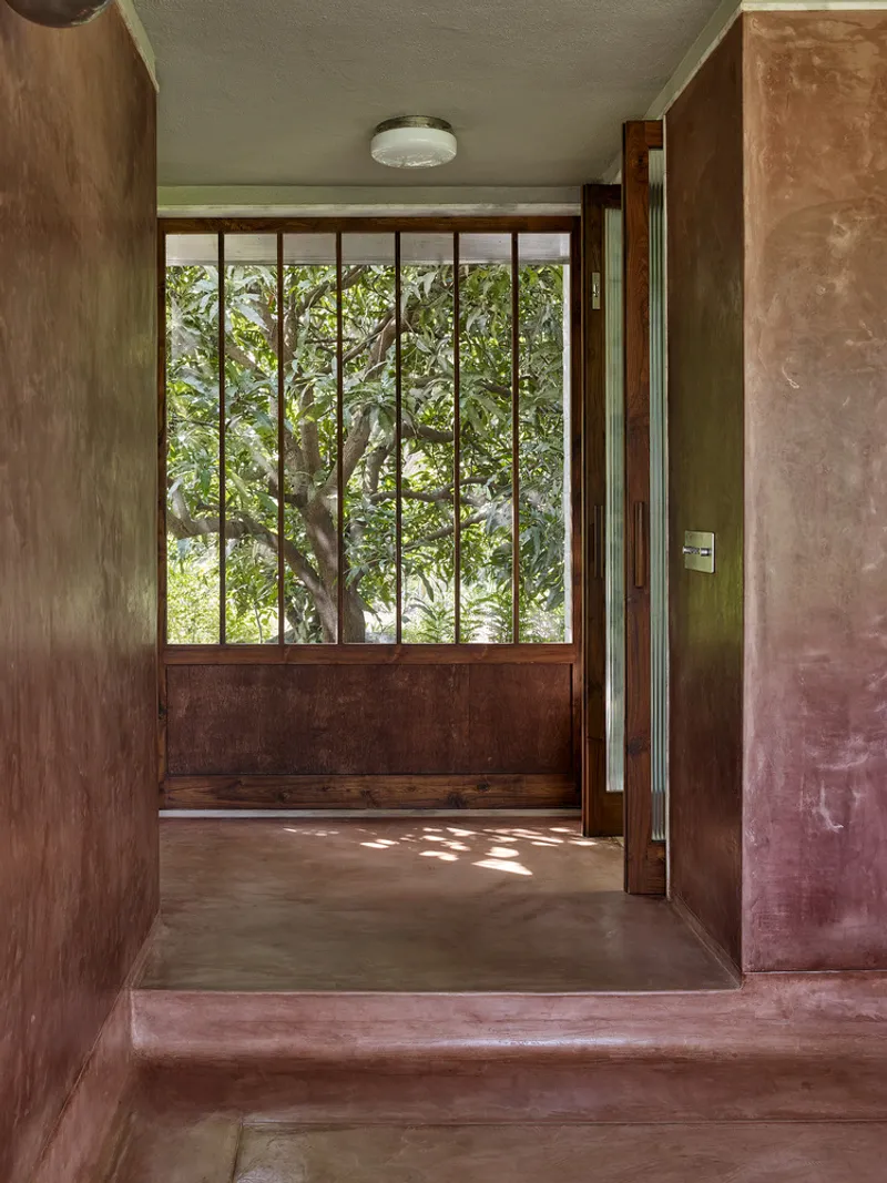 Entry vestibule with polished terracotta floor and vertical timber screen opening to garden courtyard