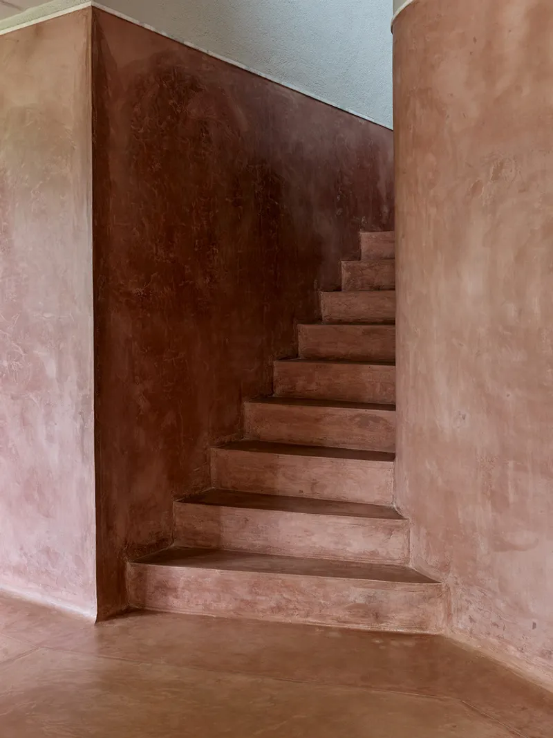 Corner staircase with terracotta plaster treads and walls curving upward between rounded column