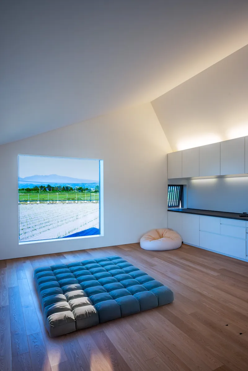 Minimal room with a square window framing a flooded rice field and distant mountains
