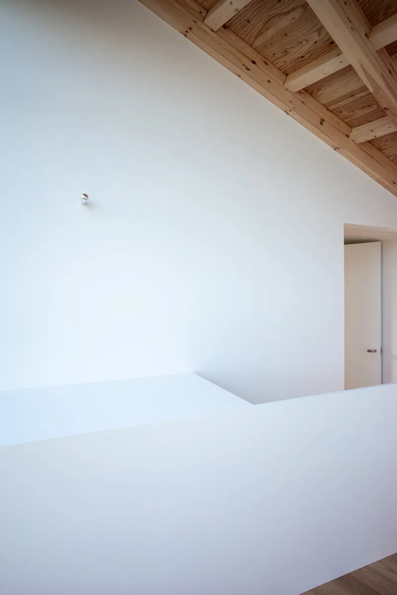 White interior wall meeting exposed timber ceiling with beams and tongue-and-groove planking