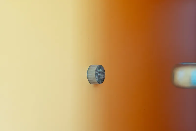 Close-up of a circular wooden door knob against a gradient orange and cream wall