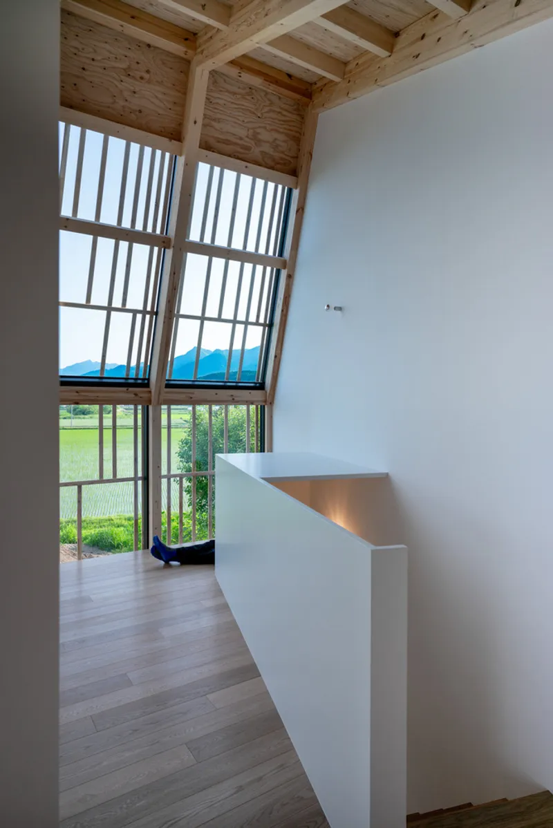 Full-height window with timber mullions overlooking green fields and a mountain range