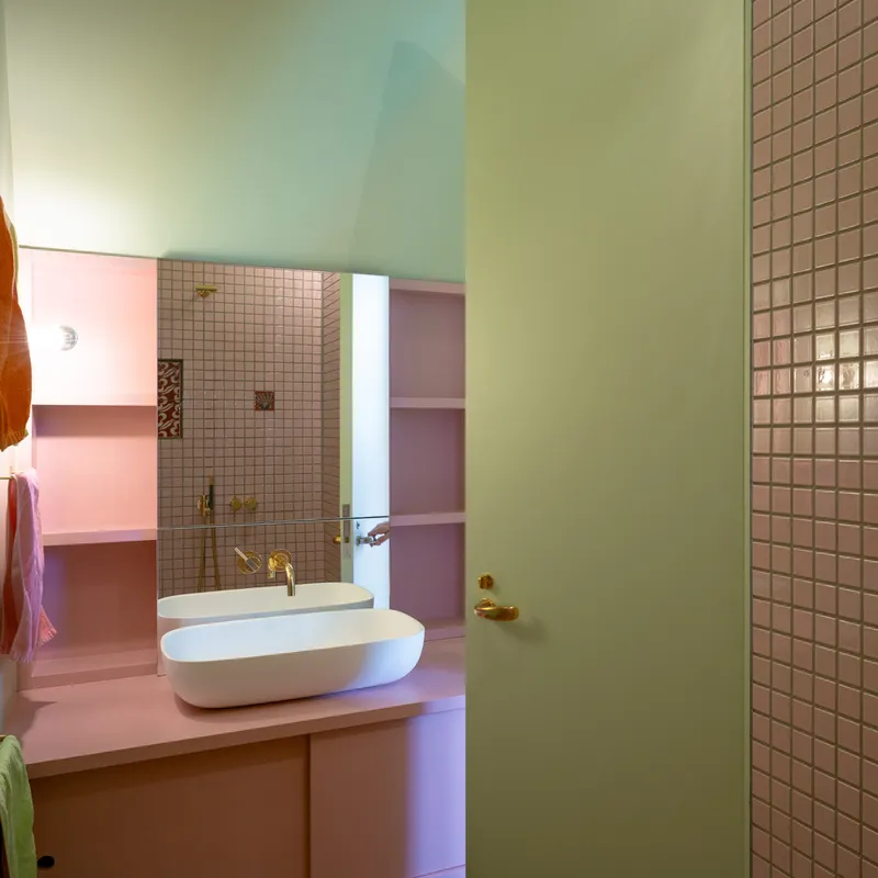 Bathroom with pink mosaic tile shower, oval sink, and mint green door