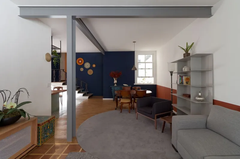 Open-plan living room with grey carpet, timber flooring, and a steel column supporting an exposed beam