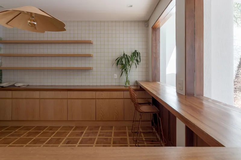 Kitchen counter with timber cabinetry, white tile backsplash, floating shelves, and a hanging pendant light
