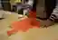 The image shows a person fixing two pieces of orange fabric together using liquid stitch. The fabric