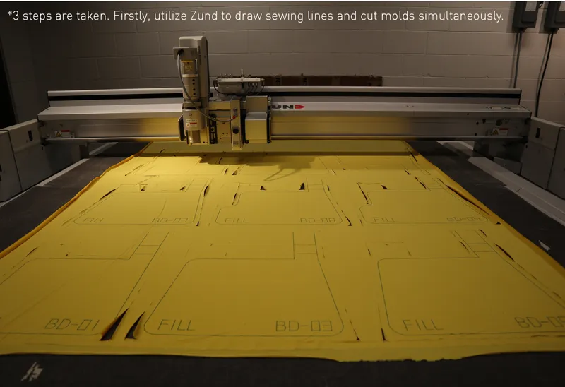 CNC cutting machine with yellow foam sheet marked with pattern lines in workshop setting