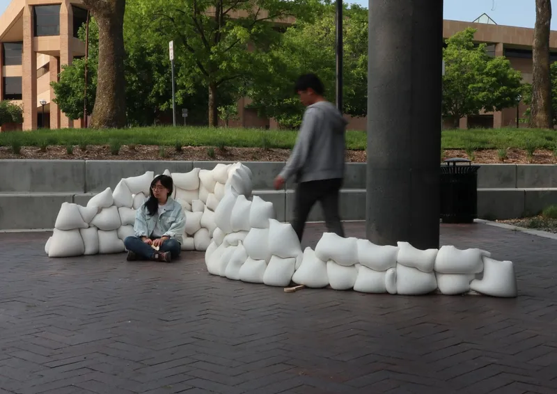 White modular seating installation on brick pavers with two people and trees in background