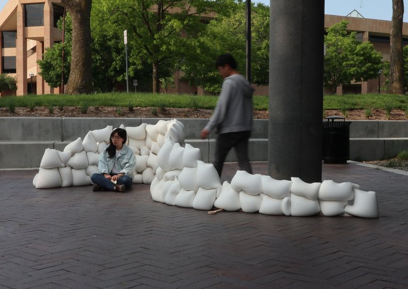 White modular seating installation on brick pavers with two people and trees in background