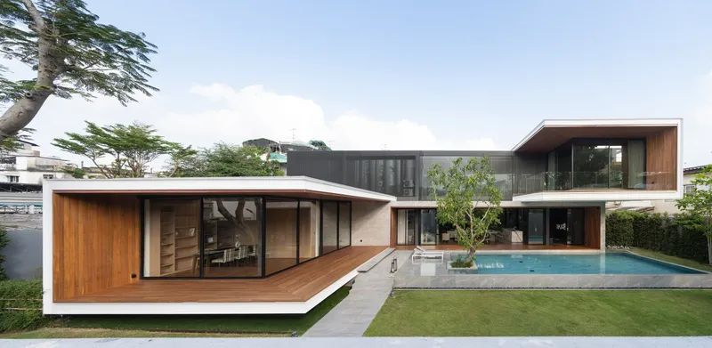 Garden view of two stacked volumes with timber cladding and a swimming pool flanked by mature trees