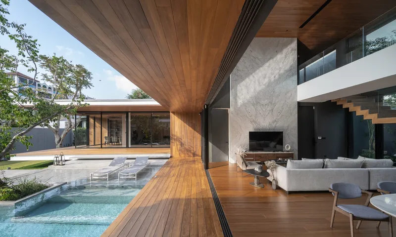 Living space opening to pool deck with timber soffit overhead and afternoon light filtering through trees