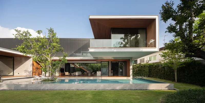 Two-storey facade with stacked glass-walled volumes and timber-clad cantilever beside the swimming pool