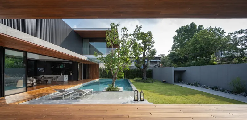 Poolside deck with lounge chairs and planted island framed by timber soffits and lawn