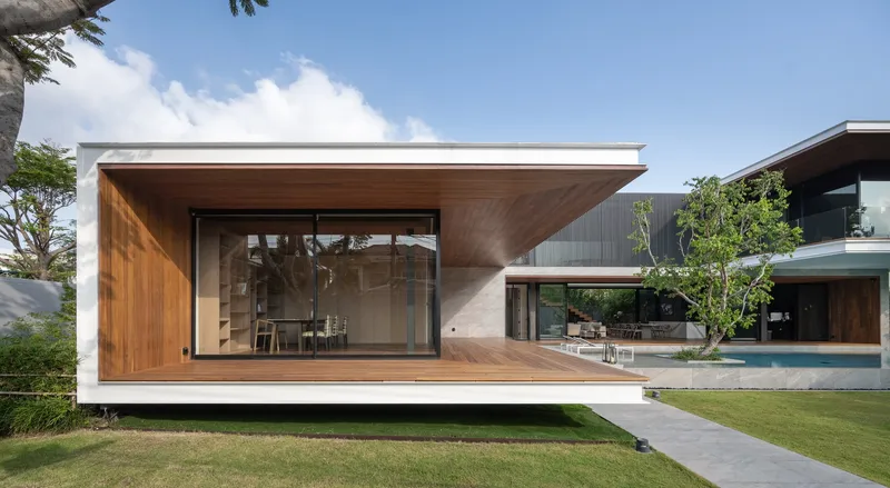 Front elevation of the timber and concrete pavilion with floor-to-ceiling glazing overlooking the lawn