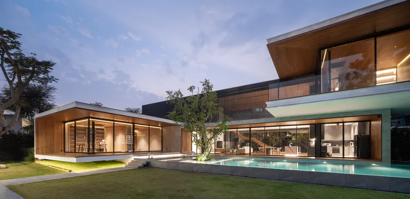 Garden elevation showing gabled timber pavilion and raised pool terrace at dusk with interior lights glowing