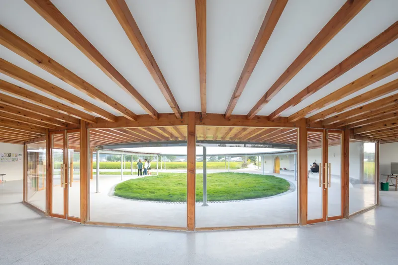 Interior view through timber framed glazing looking out to the circular grassed courtyard