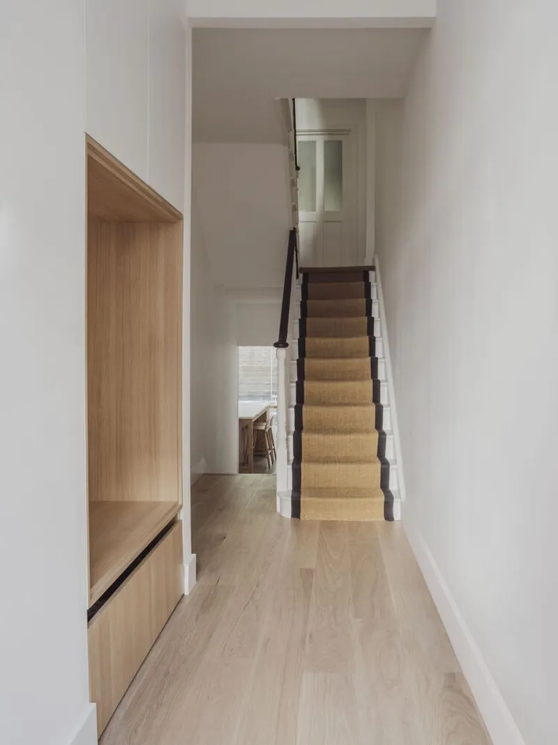 Hallway with built-in oak bench and staircase with black metal balustrade