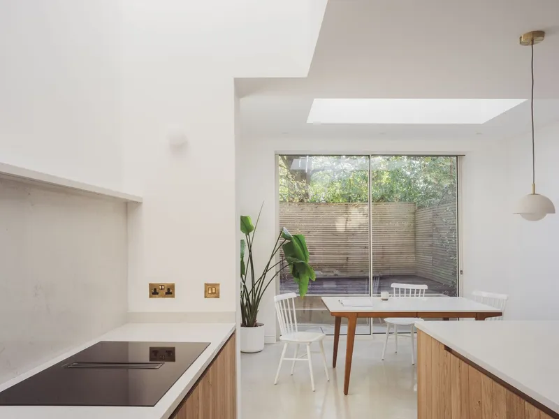 Dining area with skylight and full-height window overlooking timber-screened courtyard