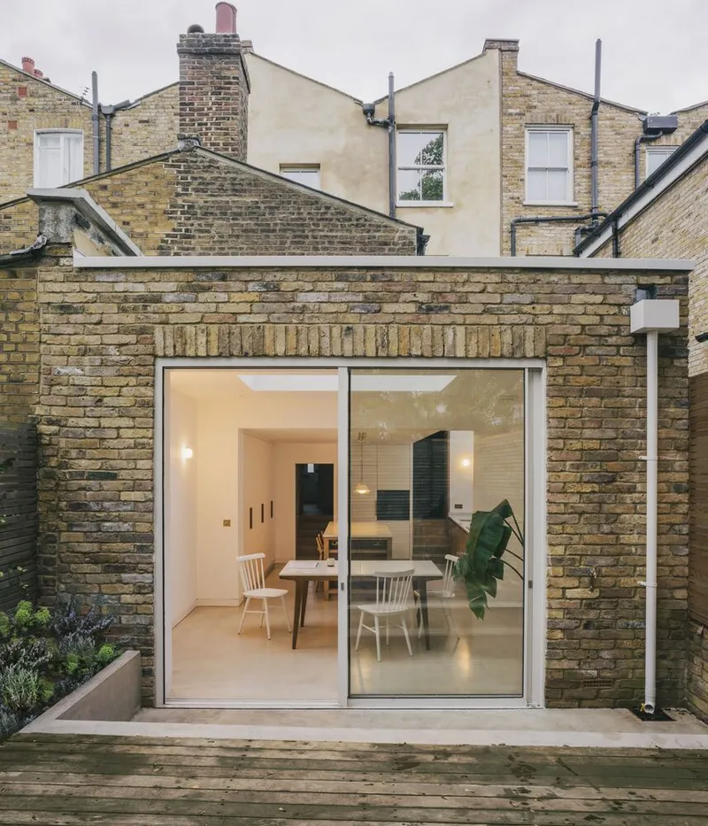 Rear extension with full-height glazed doors opening to timber deck and yellow brick boundary walls