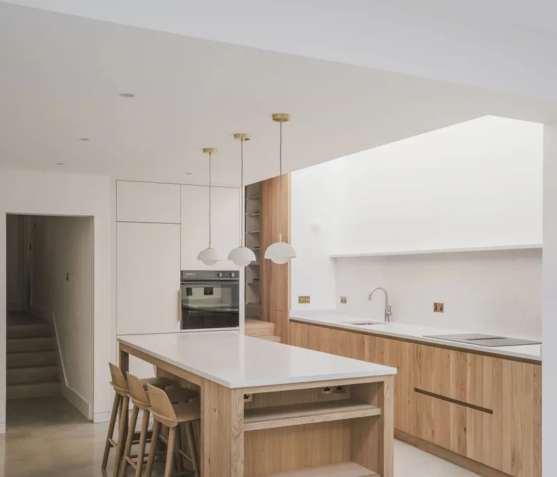 Kitchen with oak island, white cabinetry, three brass pendant lights and concrete floor