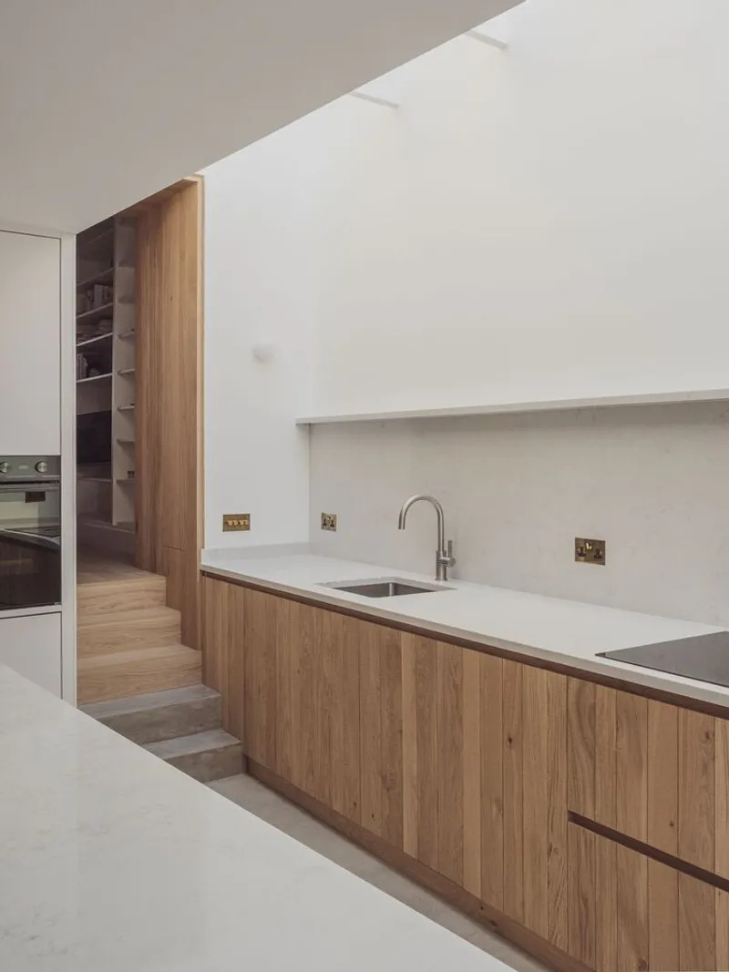 Oak base cabinets with white countertop and recessed sink beneath a concrete step detail