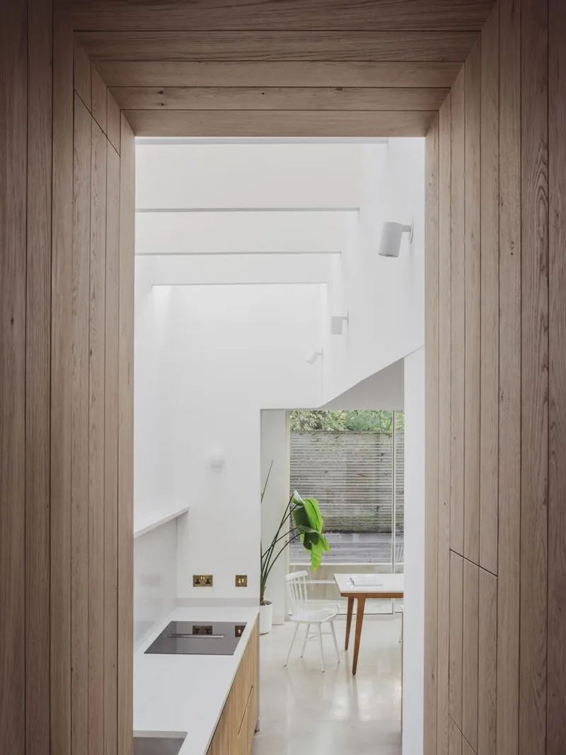 Timber-lined passageway framing views through to a dining area with horizontal slatted screens outside