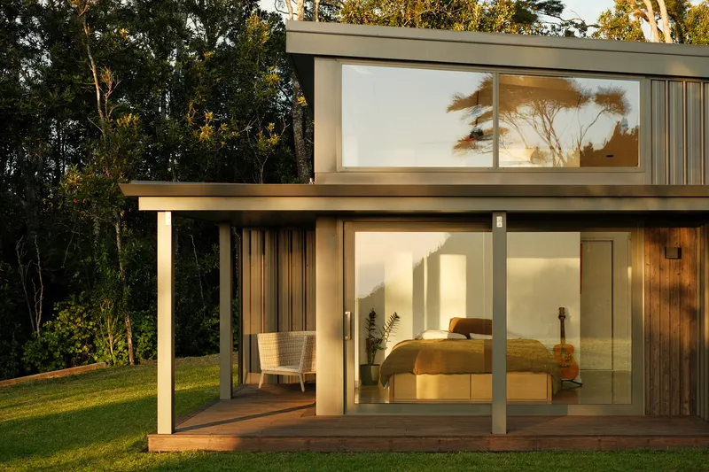 Two-storey bedroom wing with covered timber deck and full-height glazing at dusk