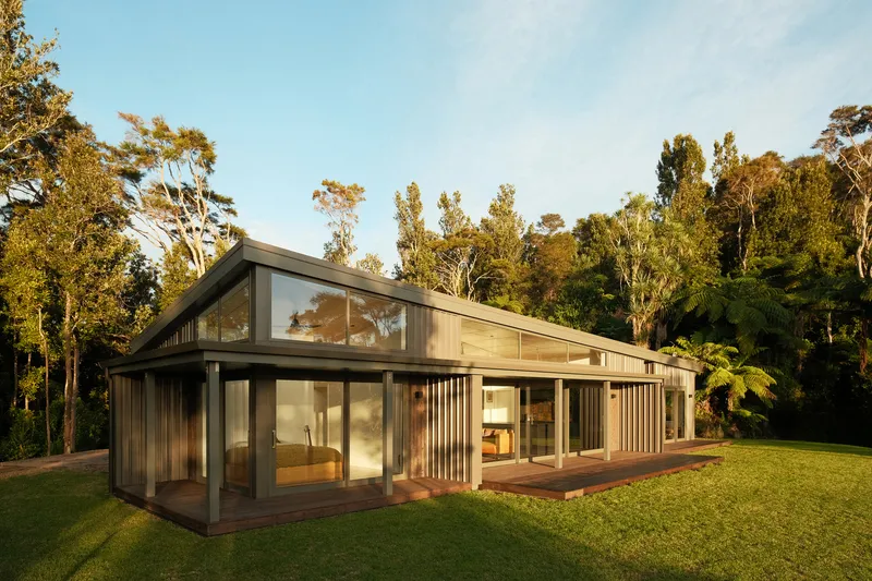 Timber and glass pavilion with vertical slat screens and a gabled roof in golden afternoon light