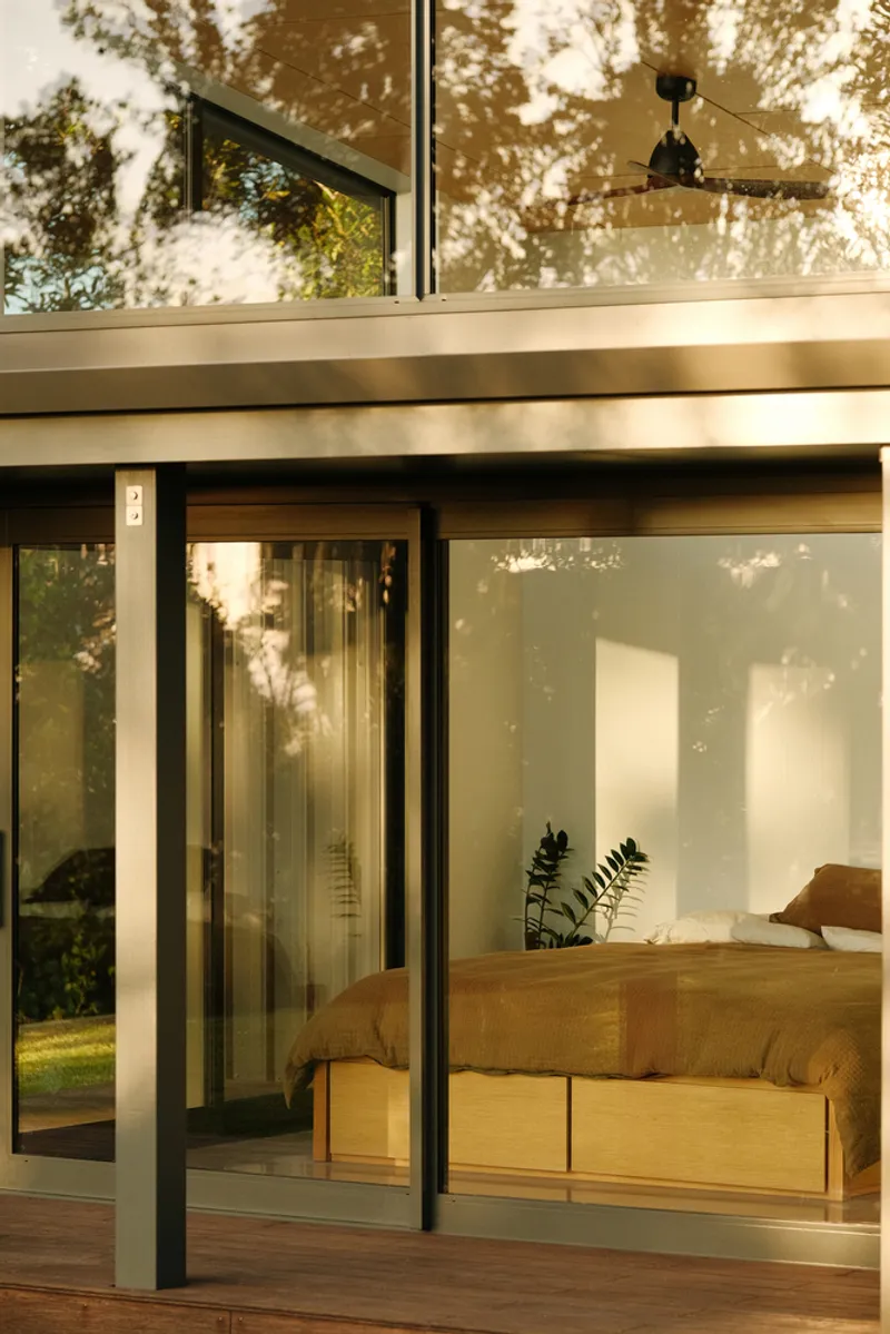 Close-up of sliding glass doors and upper clerestory windows with ceiling fan visible in reflected light