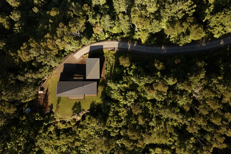 Aerial view of the angular roof surrounded by dense forest canopy in late afternoon sun