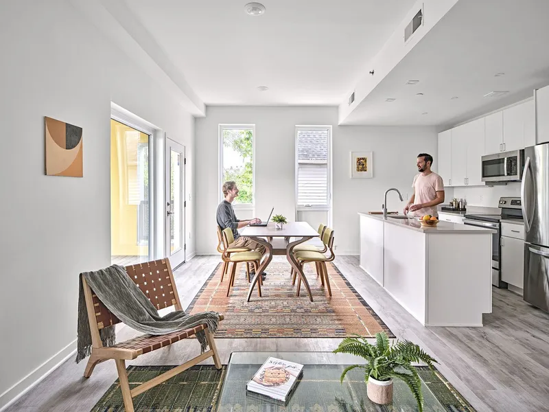 Open-plan living and kitchen space with two residents and glazed doors overlooking neighboring houses