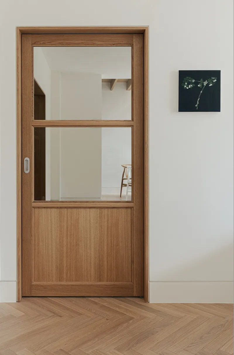 Timber pocket door with horizontal rail and glazed panels opening to a corridor beyond