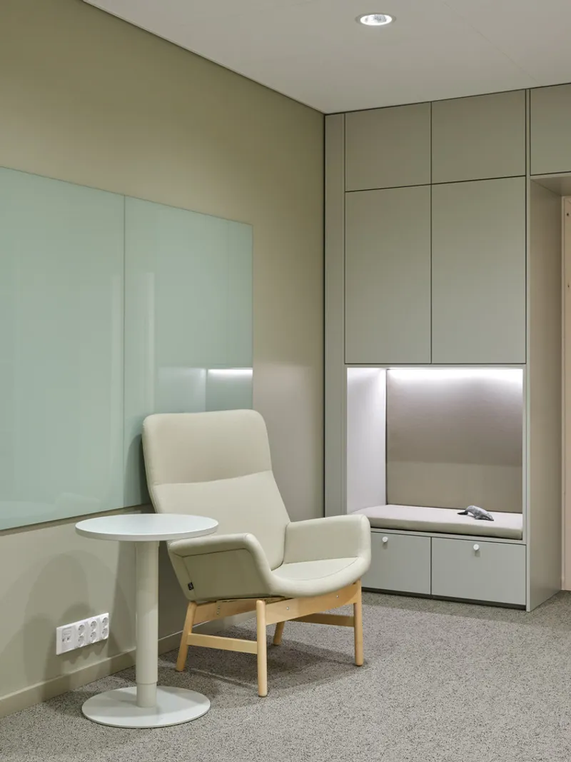 Corner seating nook with white armchair and round table beneath recessed downlight
