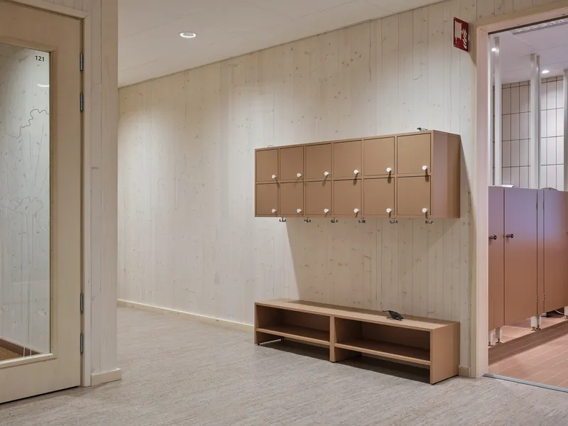Entryway with wall-mounted locker boxes and low bench against pale timber paneling