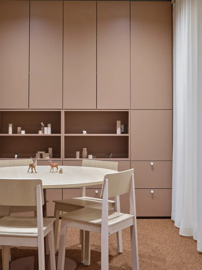 Activity table with toy animals beneath built-in birch cabinetry and open shelving